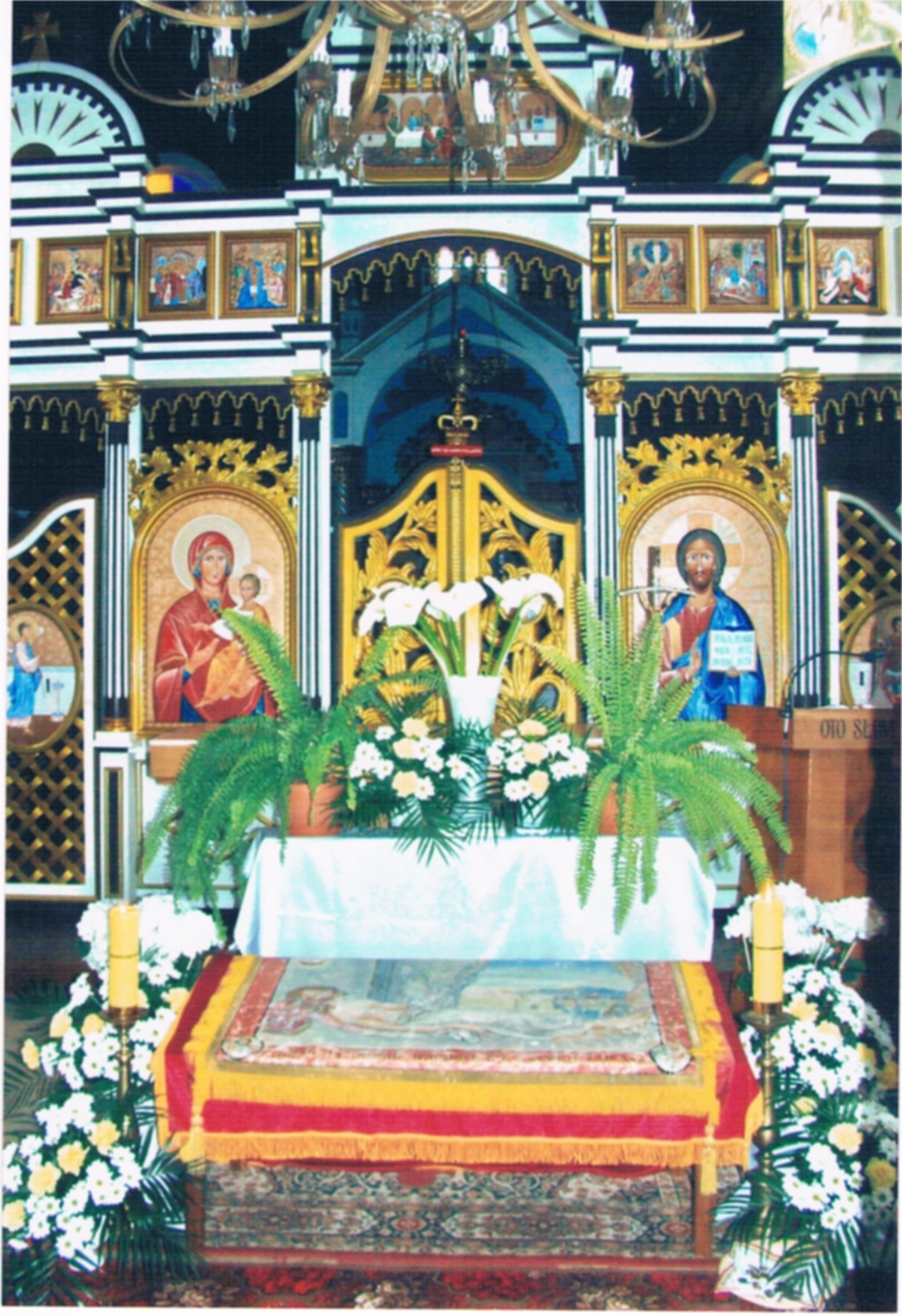 Płaszczenica wystawiona do adoracji w cerkwi - wokół płaszczenicy kwiaty i obrazy świętych